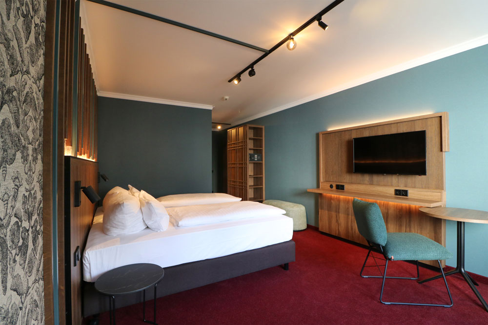 Hotelzimmeransicht vom Doppelbett und der TV-Bank bei Tageslicht