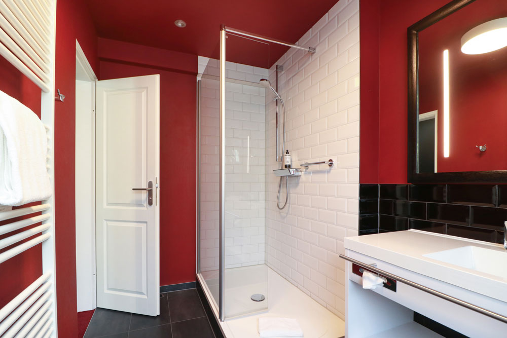 Badezimmer mit offener Tür, roten Wänden, Dusche, Heizung und Waschbecken bei Tageslicht