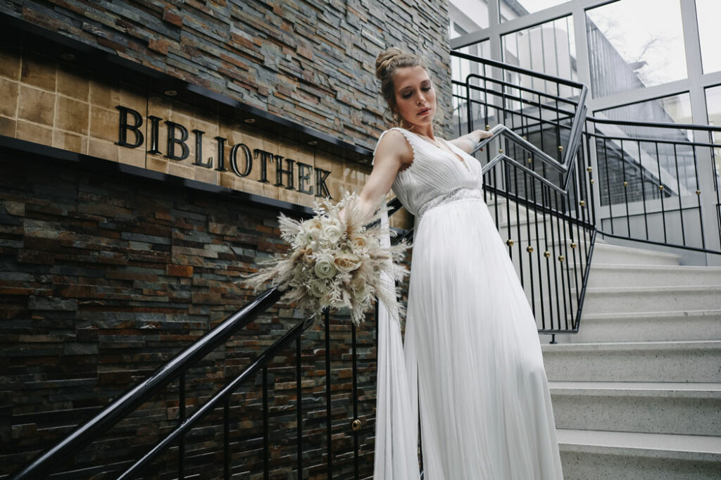 Frau im Brautkleid, die sich auf einem Treppengeländer aufstützt