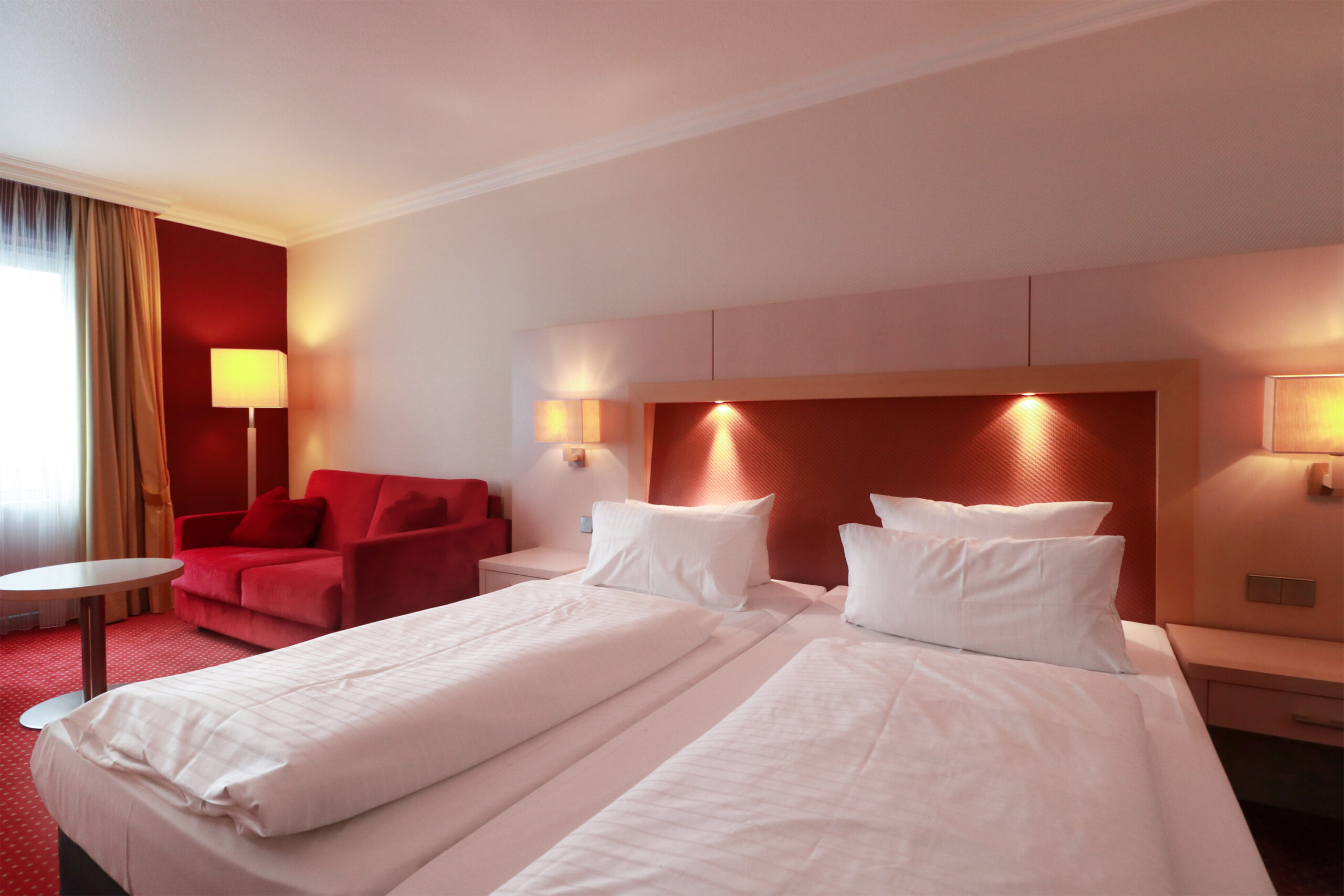 Beleuchtetes Dreibettzimmer mit Doppelbett und Schlafsofa