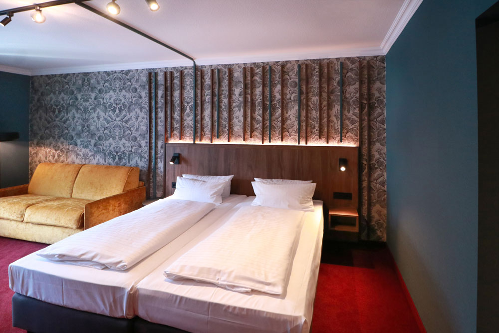 Helles geräumiges Hotelzimmer mit Sofa sowie Doppelbett