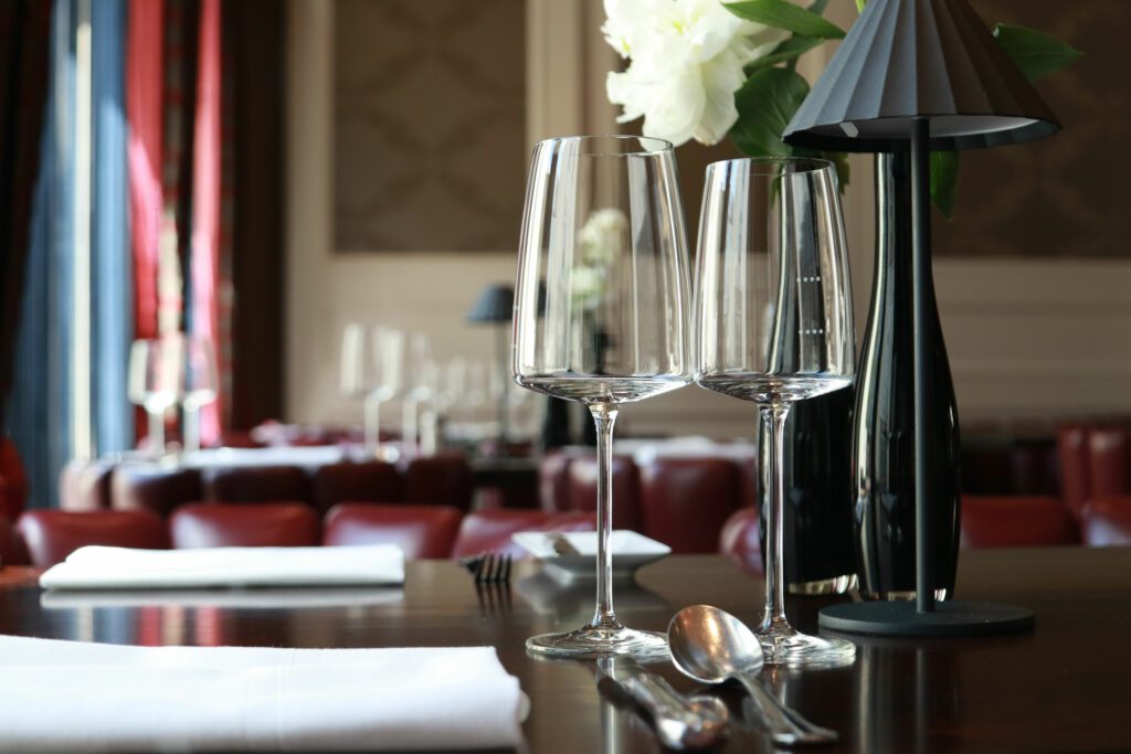 Gedeckter Tisch mit leeren Weingläsern und Blumen